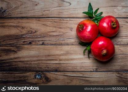 Top view of fresh juicy pomegranates whole and cut, with leaves on a wooden background. Copy space. Concept fresh fruits