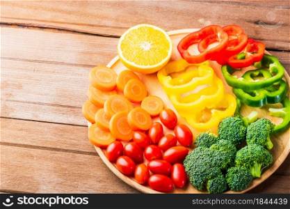 Top view of fresh organic fruits and vegetables in plate wood (carrot, Broccoli, tomato, orange, Bell pepper) on wooden table, Healthy lifestyle diet food concept
