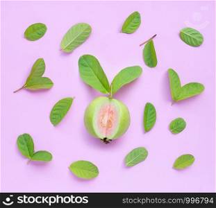 Top view of fresh ripe guava and slices with leaves on pink background.