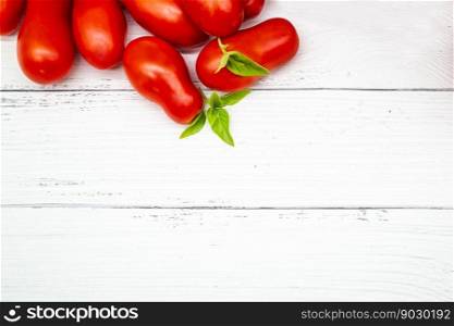 Top view of fresh tomatoes and basil on white wooden background. Copy space.