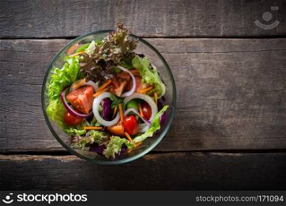 Top view of fresh vegetable salad on wooden background.