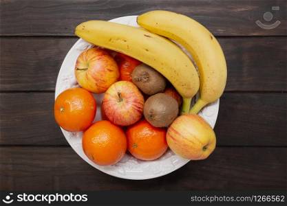 Top view of fruits in a bowl on wooden table. Healthy food concept