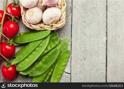 Top view of garlic, tomatoes and sugar peas over wooden table