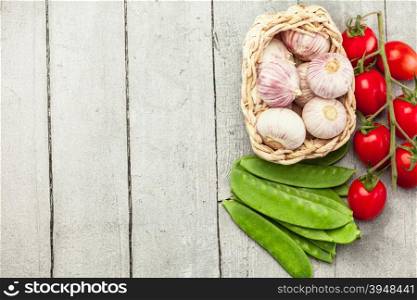 Top view of garlic, tomatoes and sugar peas over wooden table