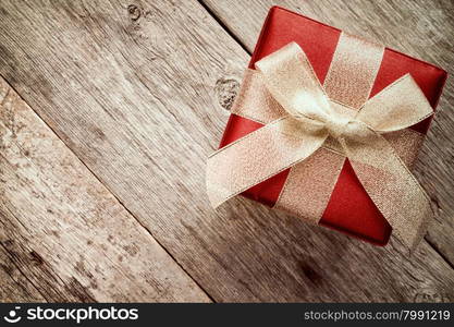 Top view of giftbox with golden bow on a wood background