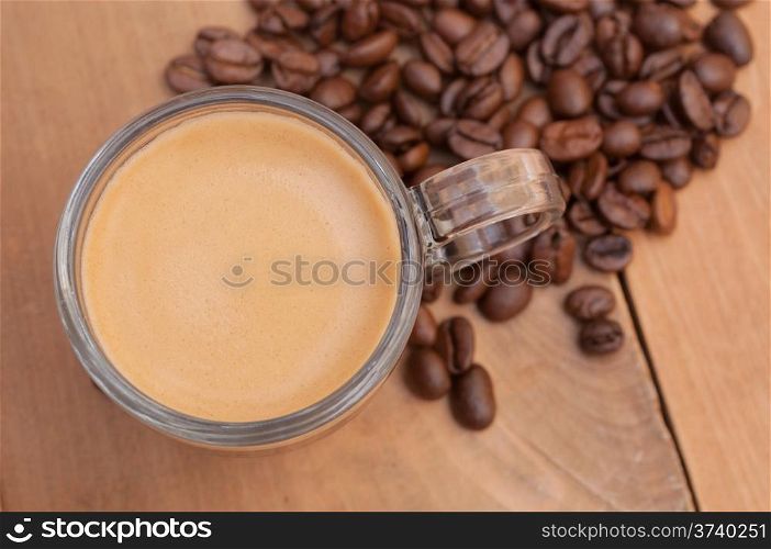 Top View of Glass Cup of Espresso Coffee on Wooden Table With Coffee Beans - Shallow Depth of Field