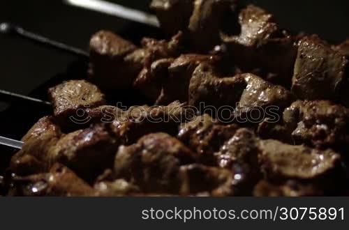 Top view of grilling meat kebabs on metal skewers on the barbecue coals outdoors