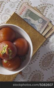 Top view of gulab jamun and currency