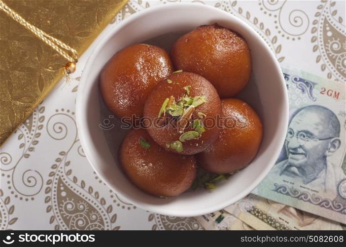 Top view of gulab jamun and currency
