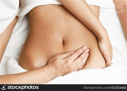 Top view of hands massaging female abdomen.Therapist applying pressure on belly. Woman receiving massage at spa salon