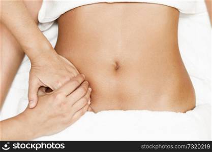 Top view of hands massaging female abdomen.Therapist applying pressure on belly. Woman receiving massage at spa salon. Hands massaging female abdomen.Therapist applying pressure on belly.