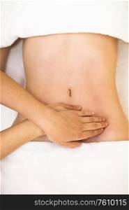 Top view of hands massaging female abdomen.Therapist applying pressure on belly. Woman receiving a belly massage at spa salon