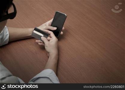 top view of hands using mobile phone and holding credit card with social media diagram as Online shopping concept
