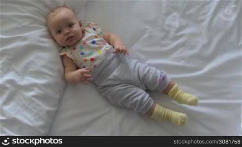 Top view of happy and active baby girl of six months old lying on the bed at home