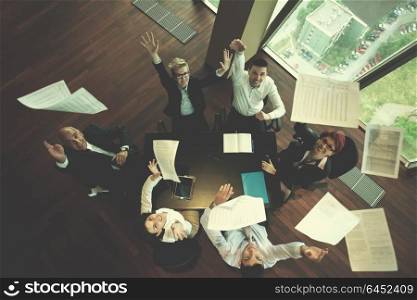 top view of happy business people group on meeting throwing documents in air at modern office interior