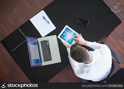 top view of happy young business man, work tablet and laptop and relax at modern bright office interior, successful hipster with beard at workplace