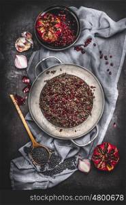 Top view of Healthy vegetarian black lentil salad with pomegranate and cooking ingredients on dark rustic background with napkin. Country dark style