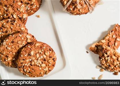 Top view of homemade oatmeal cookies with flax and sesame seeds on a white table. Healthy fitness food concept. Milk and biscuits, healthy breakfast food. Layout of Christmas cookies on a plate