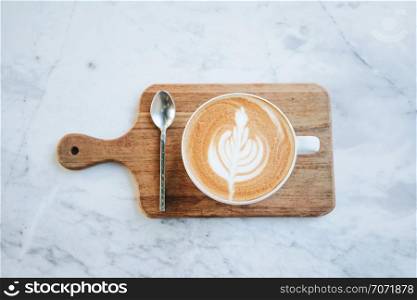 Top view of hot latte coffee on wooden tray on marble table background