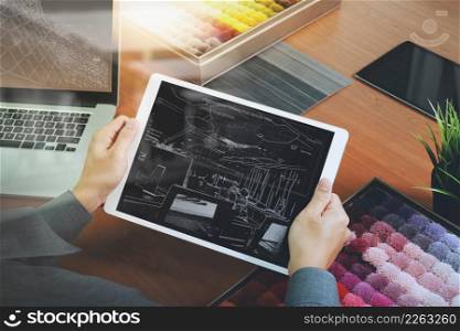 top view of Interior designer hand chosing carpet sample with blank new modern computer laptop and pro digital tablet with material board and digital design diagram layer on wooden desk as concept