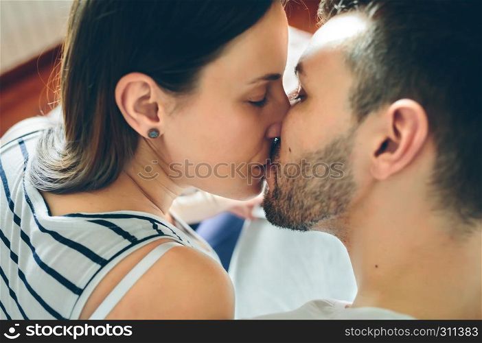 Top view of kissing couple sitting on the bed. Top view of kissing couple