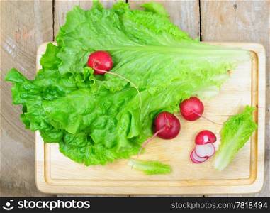 Top view of lettuce and radish on wooden background