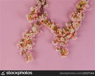 Top view of light artificial cherry blossom flowers on a soft pink background for Mothers Day or Easter holiday concept