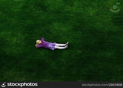 Top view of little girl lying on grass