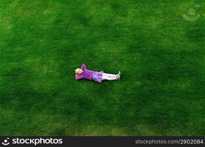 Top view of little girl lying on grass