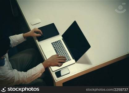 top view of man working with business documents on office table with digital tablet and man working with smart laptop computer 
