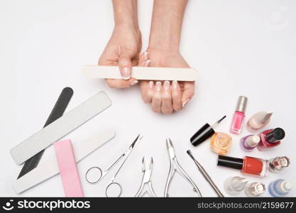 top view of manicure tools set for nail care over light background - brush, scissors, nail polish, file and tweezers.. top view of manicure tools set for nail care over light background - brush, scissors, nail polish, file and tweezers