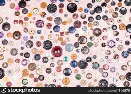 top view of many different buttons on pink background