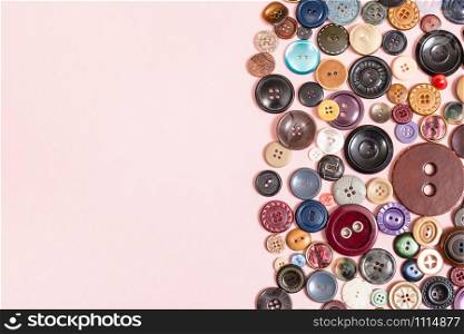 top view of many various buttons on pink background with blank copyspace