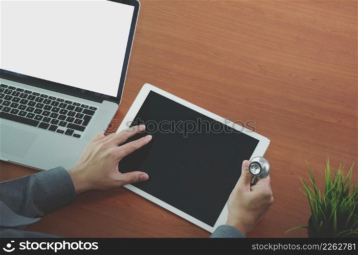 top view of Medicine doctor hand working with modern computer and digital pro tablet with blank screen on wooden desk as medical concept