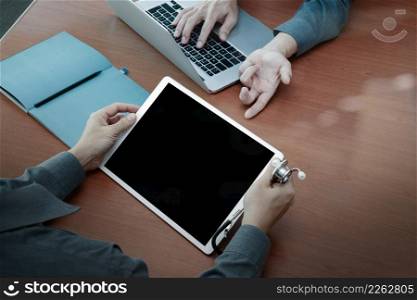 top view of Medicine doctor hand working with modern computer and digital pro tablet with blank screen with his team on wooden desk as medical concept