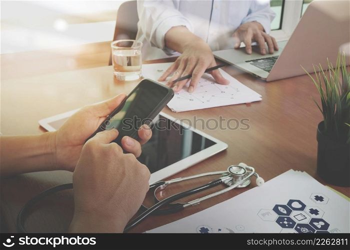 top view of Medicine doctor hand working with modern computer and digital pro tablet and smart phone with digital medical diagram with his team on wooden desk as medical concept