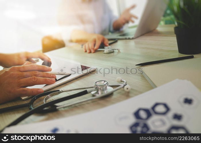 top view of Medicine doctor hand working with modern computer and digital pro tablet with blank screen with his team on wooden desk as medical concept