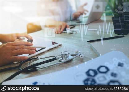 top view of Medicine doctor hand working with modern computer and digital pro tablet with digital medical diagram with his team on wooden desk as medical concept
