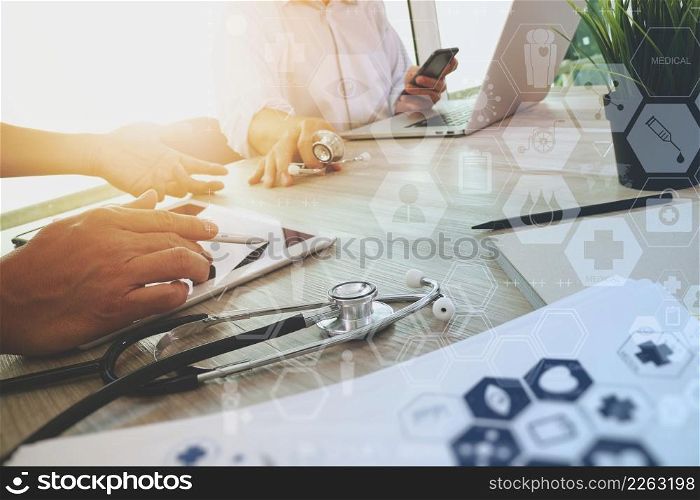 top view of Medicine doctor hand working with modern computer and digital pro tablet with digital medical diagram with his team on wooden desk as medical concept