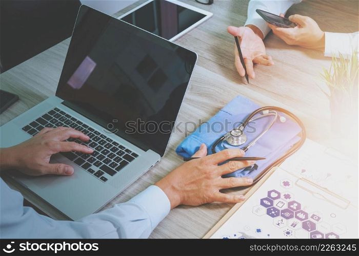 top view of Medicine doctor hand working with modern computer and digital pro tablet with his team on wooden desk as medical concept