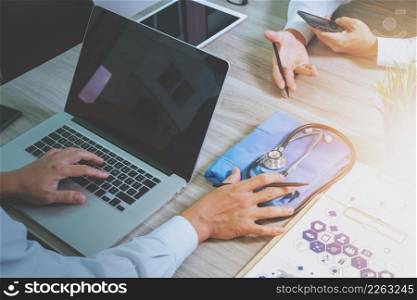 top view of Medicine doctor hand working with modern computer and digital pro tablet with his team on wooden desk as medical concept