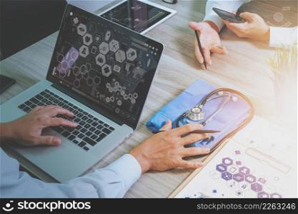 top view of Medicine doctor hand working with modern computer and digital pro tablet with his team with digital medical diagram on wooden desk as medical concept
