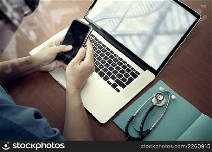 top view of Medicine doctor hand working with modern computer and smart phone with social media network on wooden desk as medical concept