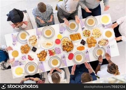 top view of modern multiethnic muslim family praying before having iftar dinner together during a ramadan feast at home