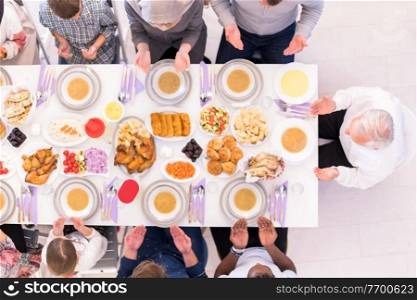 top view of modern multiethnic muslim family praying before having iftar dinner together during a ramadan feast at home