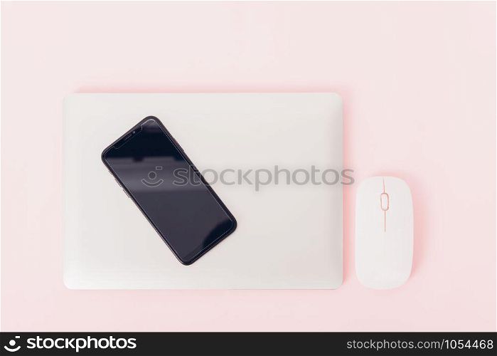 Top view of modern technology smart phone mobile and computer laptop close cover on pink background with copy space