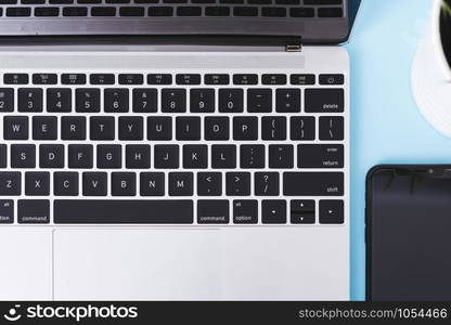 Top view of modern technology smart phone mobile and computer laptop on blue background with copy space