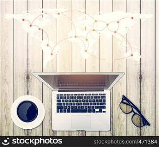 Top view of modern working business office desk - notebook or laptop with connection worldmap network on wood table texture background, communication concept.