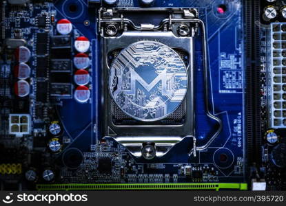 Top view of Monero cryptocurrency physical coin on computer mother board processor.Bitcoin mining farm, working computer equipment concept.