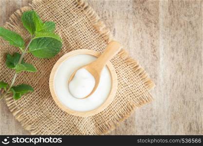 top view of natural greek yogurt in cup on old wooden table background. Yogurt is delicious tasty and healthy.